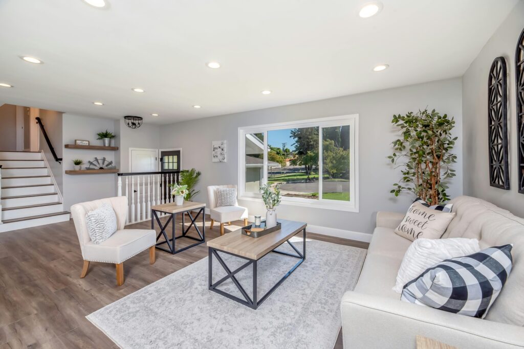 Bright and modern living room with hardwood floors, light gray walls, and white upholstered furniture, professionally cleaned and maintained by Pro-Care of Cookeville, with stylish decor and a large window offering a scenic outdoor view.